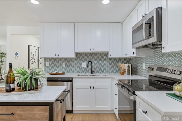 kitchen with backsplash, appliances with stainless steel finishes, sink, and white cabinets