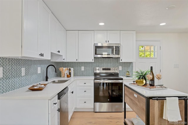 kitchen featuring backsplash, stainless steel appliances, sink, and white cabinets