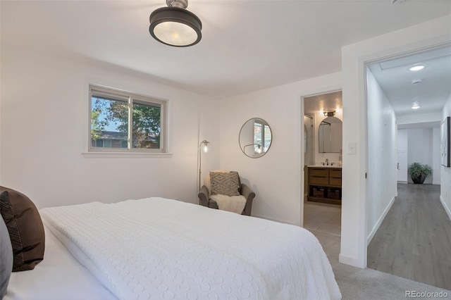 bedroom with sink, ensuite bath, and light colored carpet