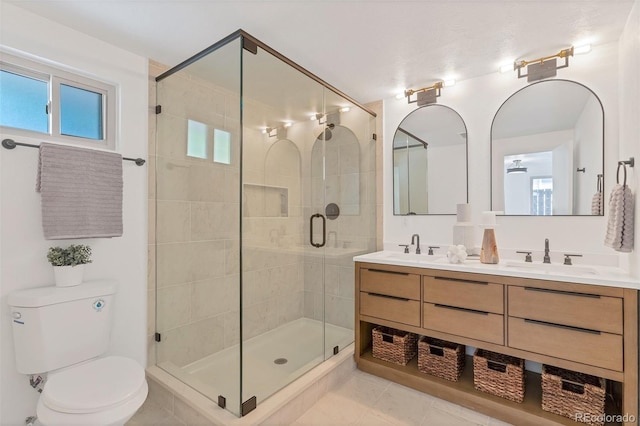 bathroom featuring tile patterned flooring, toilet, vanity, and a shower with shower door