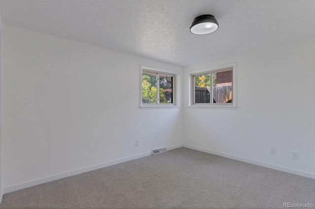 carpeted spare room featuring a textured ceiling