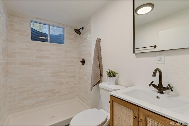 bathroom with tiled shower, vanity, and toilet