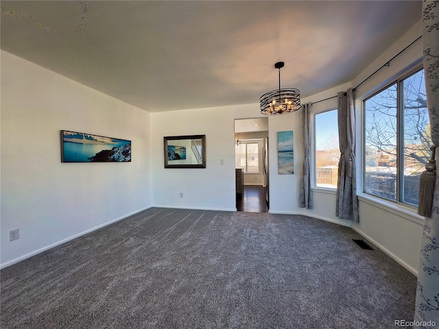 unfurnished living room with a chandelier and dark colored carpet