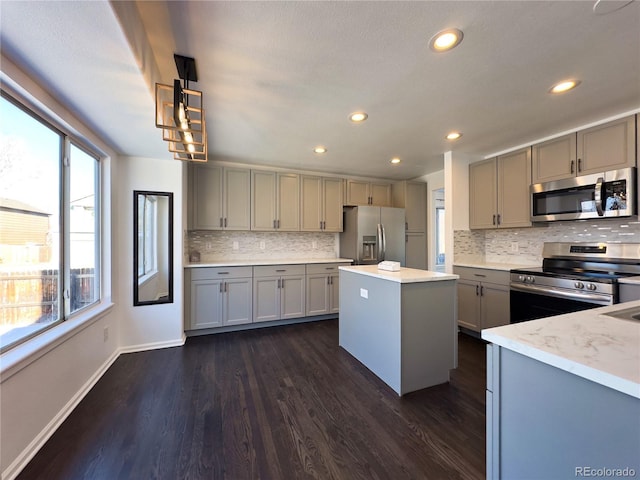 kitchen featuring appliances with stainless steel finishes, gray cabinets, dark hardwood / wood-style flooring, and a kitchen island