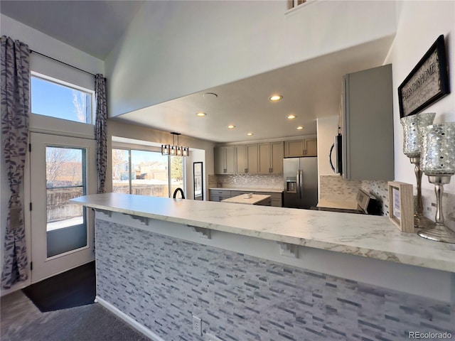 kitchen with light stone countertops, hanging light fixtures, kitchen peninsula, stainless steel appliances, and gray cabinets