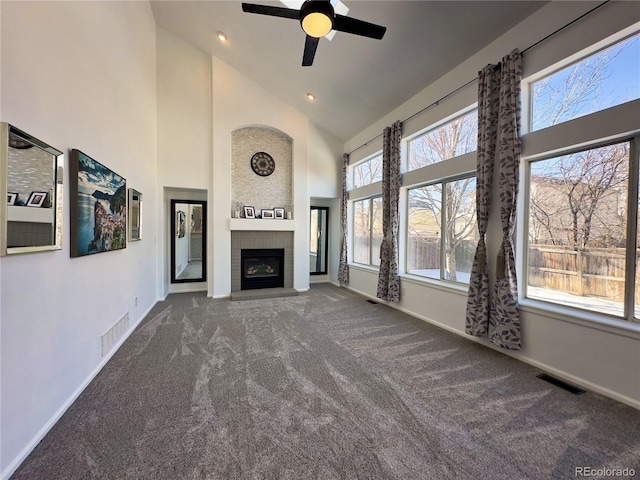 unfurnished living room featuring high vaulted ceiling, a wealth of natural light, carpet floors, and a fireplace