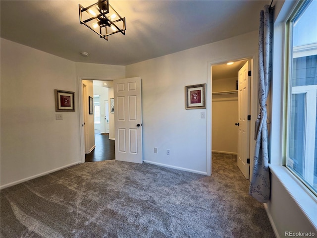 unfurnished bedroom with dark carpet, a closet, and a walk in closet