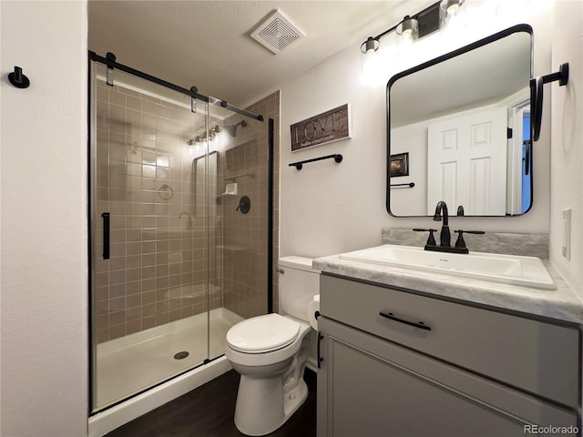 bathroom featuring a shower with shower door, wood-type flooring, toilet, and vanity