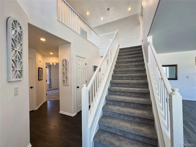 stairway with a high ceiling and wood-type flooring