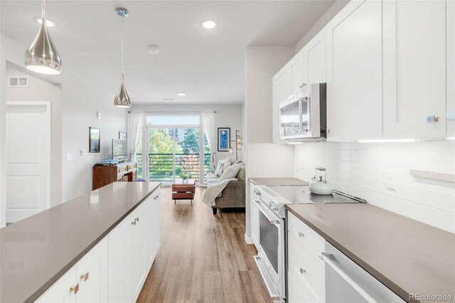 kitchen featuring white cabinetry, light wood-type flooring, stainless steel appliances, decorative light fixtures, and backsplash