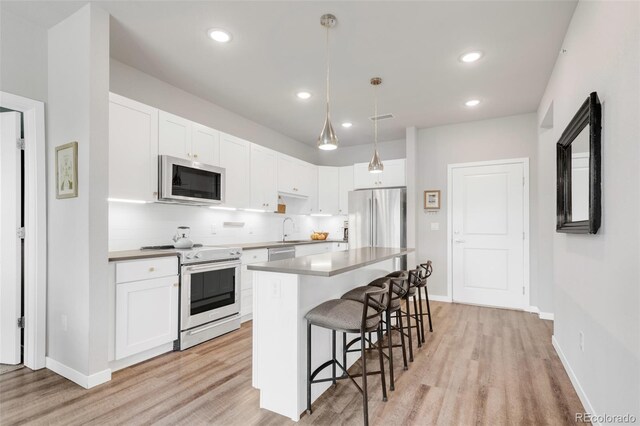 kitchen featuring white cabinets, a kitchen bar, stainless steel appliances, and a center island