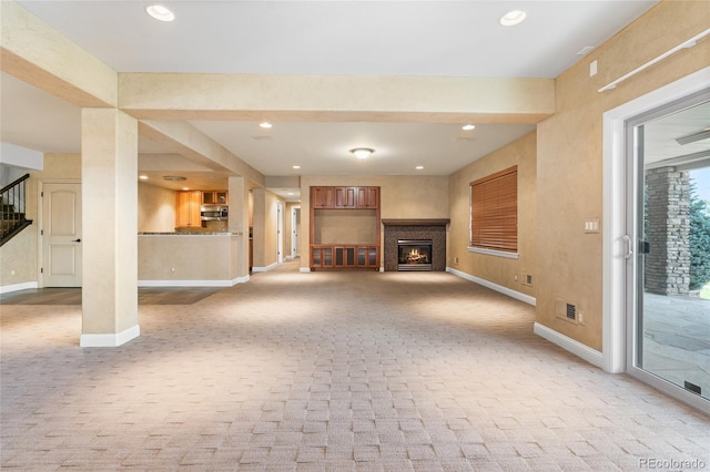 27485 E Nova Pl, Aurora, CO 80016 - unfurnished living room with light colored carpet, a glass covered fireplace, recessed lighting, and stairway