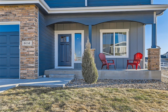 view of exterior entry with a garage and a porch