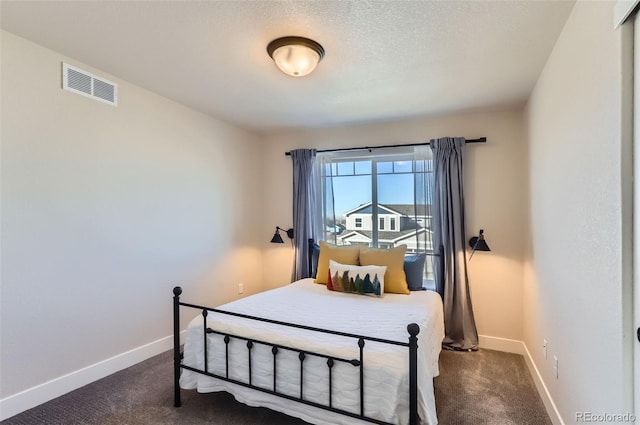 bedroom with a textured ceiling and dark colored carpet