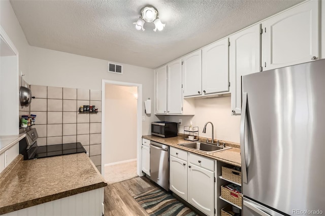 1011 Uvalda St, Aurora, CO 80011 - kitchen with stainless steel appliances, light wood-style floors, white cabinets, and a textured ceiling