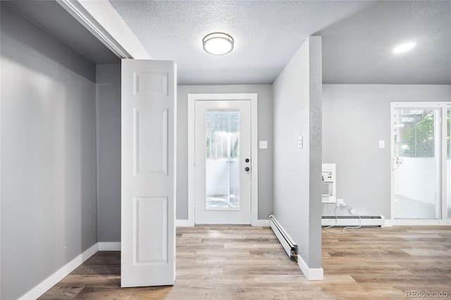 foyer entrance with a wall mounted air conditioner, a textured ceiling, a baseboard radiator, and light hardwood / wood-style floors