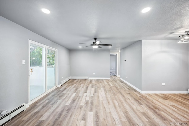 spare room featuring ceiling fan, light hardwood / wood-style floors, a textured ceiling, and a baseboard heating unit