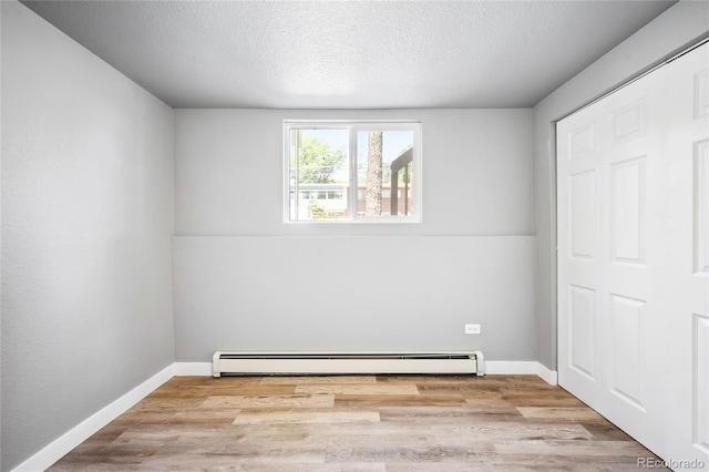 unfurnished bedroom featuring baseboard heating, a closet, light hardwood / wood-style floors, and a textured ceiling