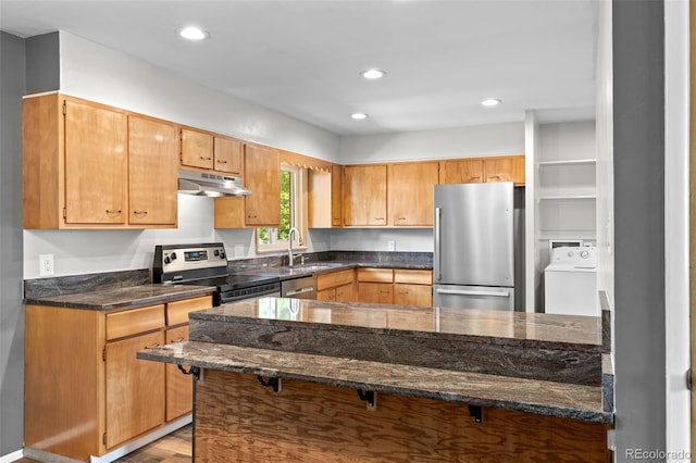 2101 Youngfield St, Golden, CO 80401 - kitchen with stainless steel appliances, washer / dryer, under cabinet range hood, a peninsula, and dark stone counters