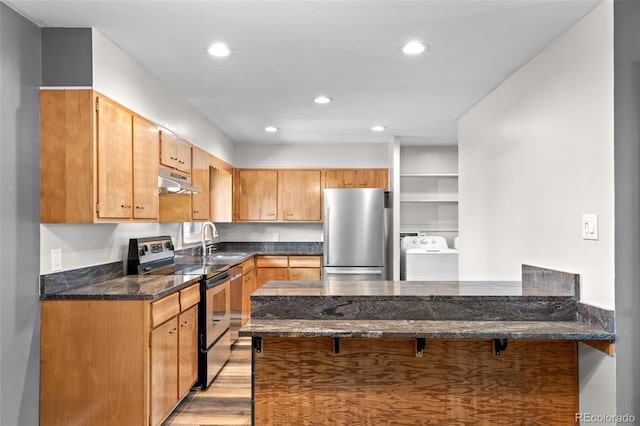 2101 Youngfield St, Golden, CO 80401 - kitchen with stainless steel appliances, under cabinet range hood, washer / dryer, a peninsula, and dark stone countertops