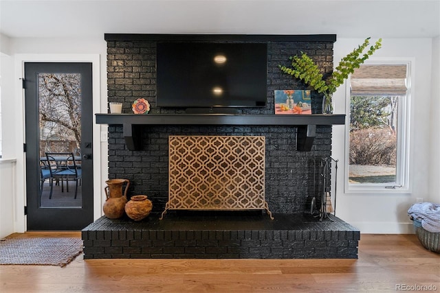 details featuring a brick fireplace, baseboards, and wood finished floors