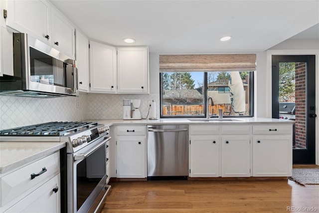 kitchen featuring a sink, appliances with stainless steel finishes, white cabinets, light wood finished floors, and light countertops