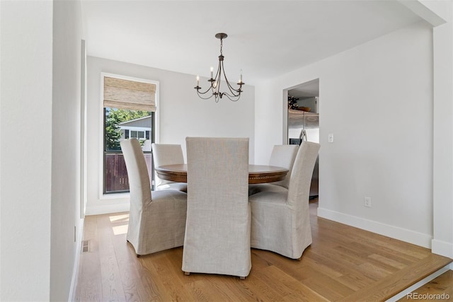 dining space featuring an inviting chandelier, light wood-style floors, baseboards, and visible vents