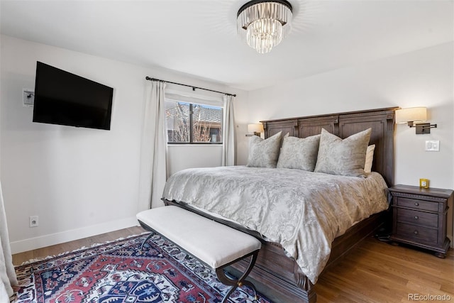 bedroom featuring a notable chandelier, light wood-style flooring, and baseboards