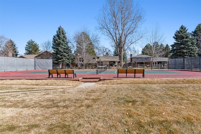 view of sport court with a lawn and fence