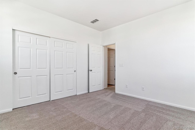 unfurnished bedroom featuring a closet and light colored carpet