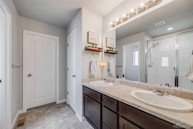 full bath with a stall shower, baseboards, and double vanity