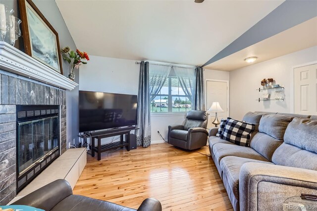 7716 Shenandoah Dr, Elizabeth, CO 80107 - living room featuring vaulted ceiling, hardwood / wood-style floors, a tiled fireplace, and baseboards