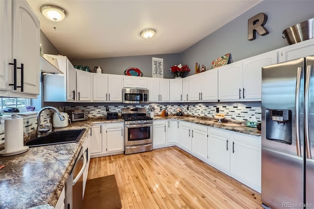 7716 Shenandoah Dr, Elizabeth, CO 80107 - kitchen with appliances with stainless steel finishes, a sink, vaulted ceiling, decorative backsplash, and white cabinets