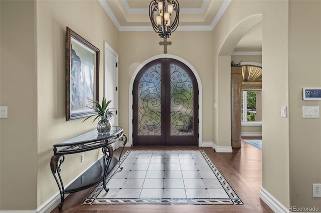 2378 Plumb Pl, Erie, CO 80516 - entrance foyer featuring arched walkways, french doors, a chandelier, ornamental molding, and wood finished floors