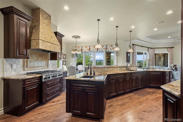 2378 Plumb Pl, Erie, CO 80516 - kitchen featuring stainless steel gas stovetop, light wood-type flooring, premium range hood, tasteful backsplash, and crown molding