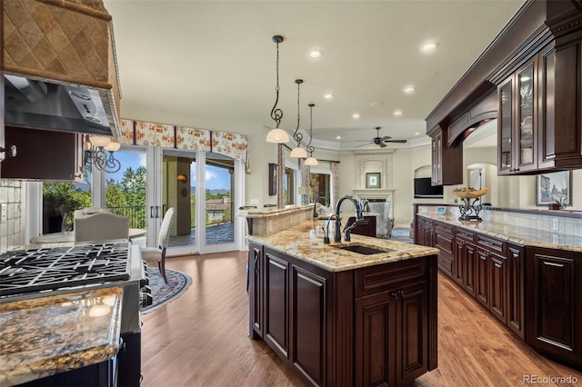2378 Plumb Pl, Erie, CO 80516 - kitchen featuring a ceiling fan, a kitchen island with sink, light wood-style floors, glass insert cabinets, and recessed lighting