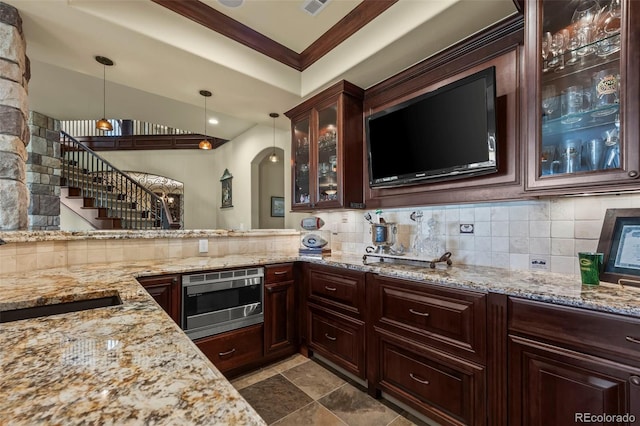 2378 Plumb Pl, Erie, CO 80516 - kitchen with tasteful backsplash, stainless steel microwave, decorative light fixtures, arched walkways, and light stone countertops