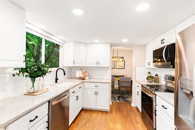 1168 E Kettle Pl, Centennial, CO 80122 - kitchen with appliances with stainless steel finishes, decorative backsplash, light wood-type flooring, white cabinets, and recessed lighting