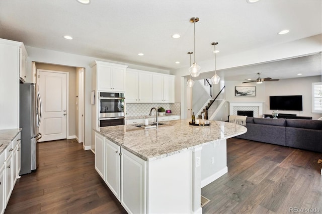 8102 Adams Fork Ave, Littleton, CO 80125 - kitchen featuring stainless steel appliances, a sink, open floor plan, a ceiling fan, and a tiled fireplace