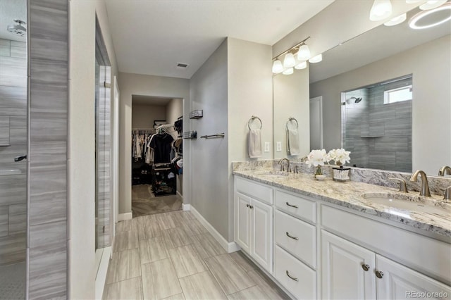8102 Adams Fork Ave, Littleton, CO 80125 - bathroom with double vanity, a tile shower, a walk in closet, and baseboards