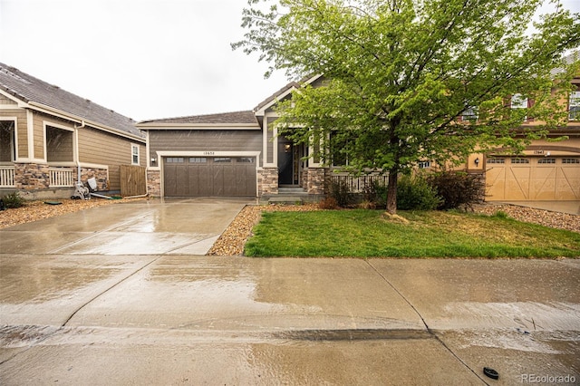 craftsman-style house with concrete driveway, an attached garage, stone siding, and a front lawn