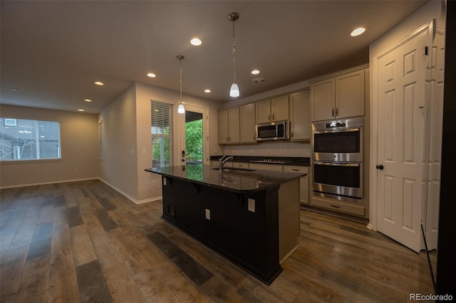 kitchen featuring appliances with stainless steel finishes, a sink, healthy amount of natural light, a center island with sink, and recessed lighting