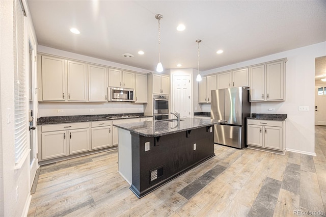 kitchen featuring stainless steel appliances, dark stone counters, a breakfast bar area, recessed lighting, and hanging light fixtures