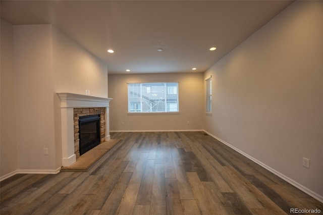 unfurnished living room featuring dark wood-style floors, recessed lighting, a fireplace, and baseboards