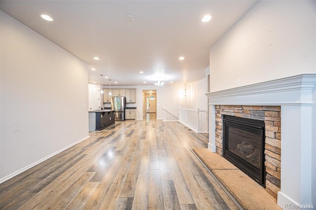 unfurnished living room with light wood-style floors, recessed lighting, baseboards, and a fireplace