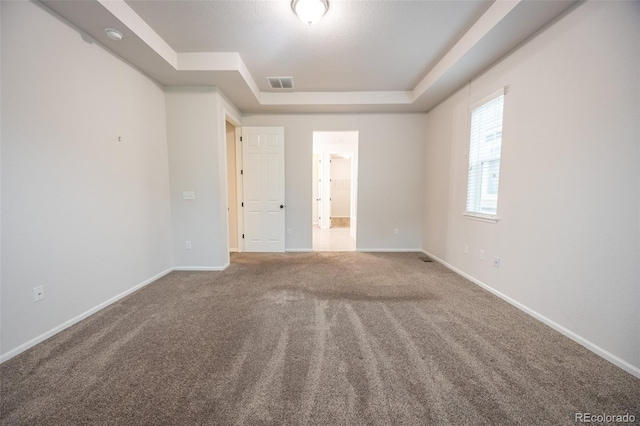 carpeted spare room with a tray ceiling and baseboards