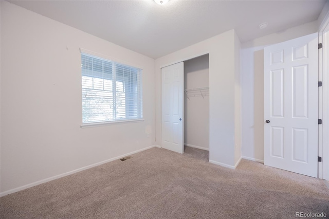 unfurnished bedroom with carpet, a closet, and baseboards