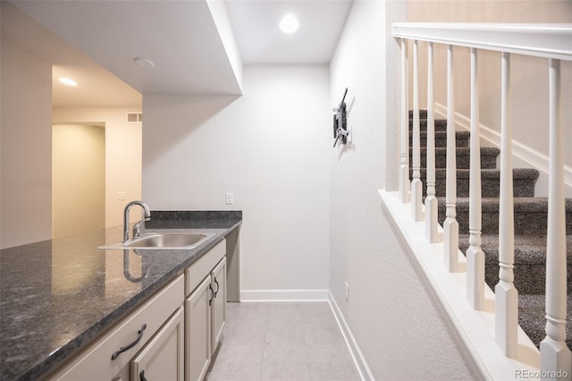 bar featuring a sink, light tile patterned floors, recessed lighting, baseboards, and stairway