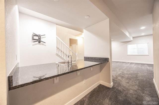 bar area with a sink, dark carpet, stairway, and baseboards