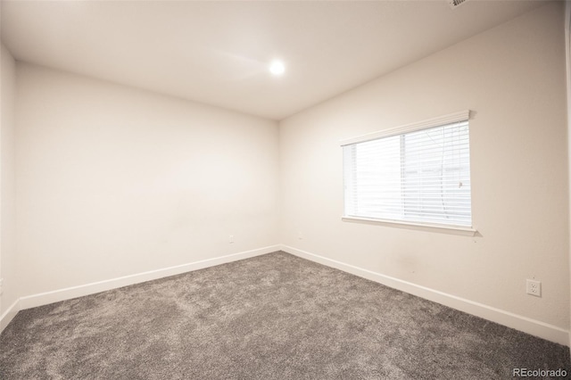 empty room with dark carpet and baseboards